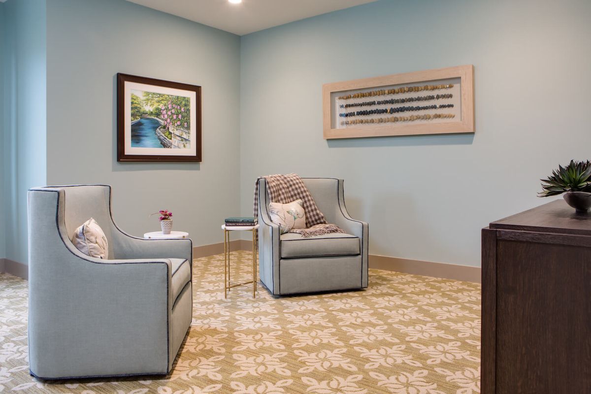 A cozy living room with armchairs and artwork on the walls.