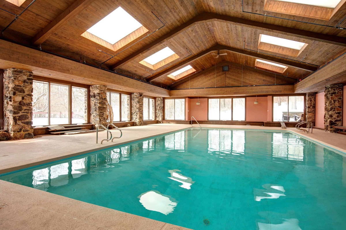 Spacious indoor swimming pool with skylights and a wooden ceiling.
