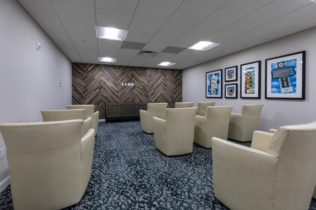 A modern waiting room with multiple cream-colored chairs and framed artwork on the walls.