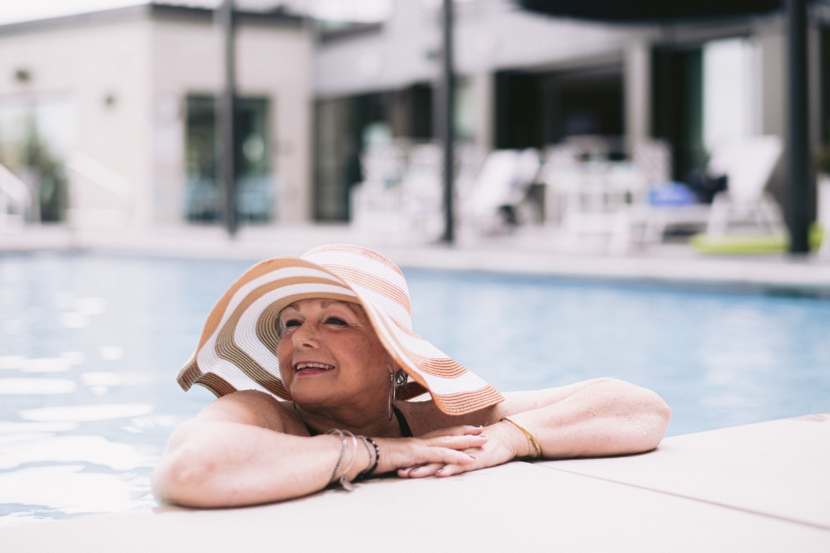 A woman enjoying a relaxing moment by the swimming pool, wearing a stylish sun hat.