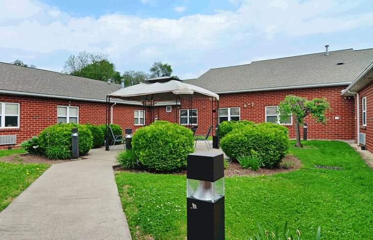 A courtyard with lush greenery and outdoor seating, surrounded by a brick building.