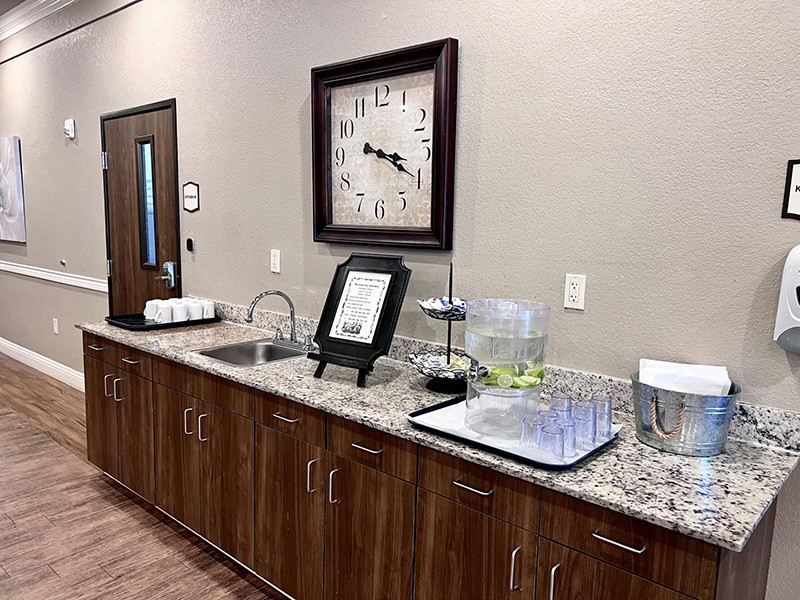 A reception area with a beverage station and clock on the wall.
