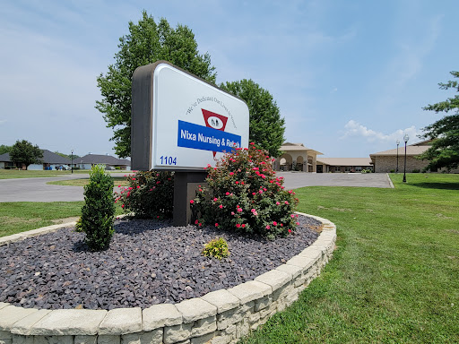 Welcome sign for a local business, surrounded by neatly landscaped flowers and greenery.