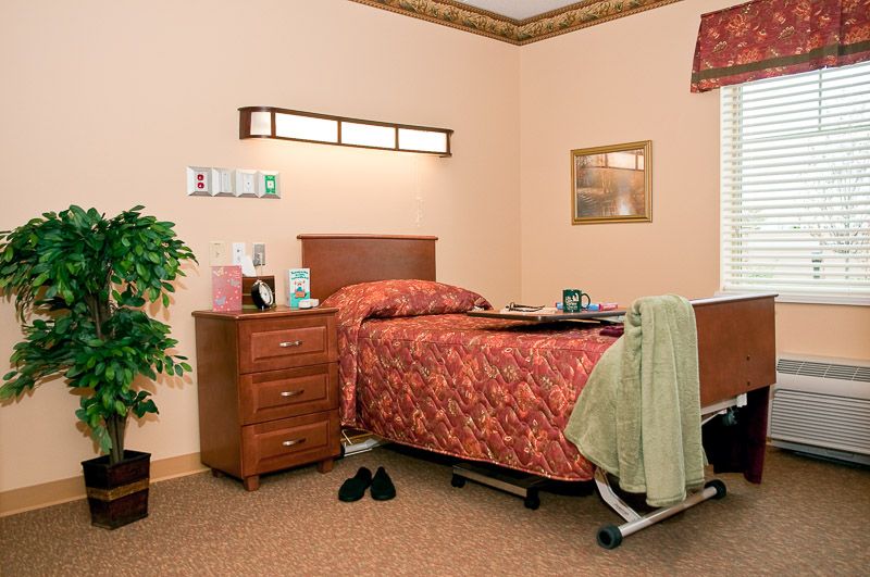 A cozy hospital room with a single bed, wooden furniture, and tasteful decor.