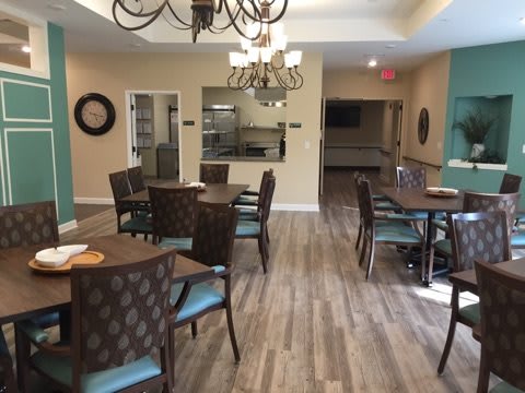 A modern dining area with neatly arranged tables and chairs, complemented by a chandelier.