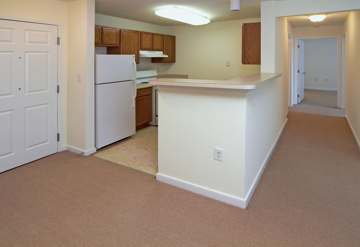 A small apartment kitchen with brown cabinets and a white fridge.