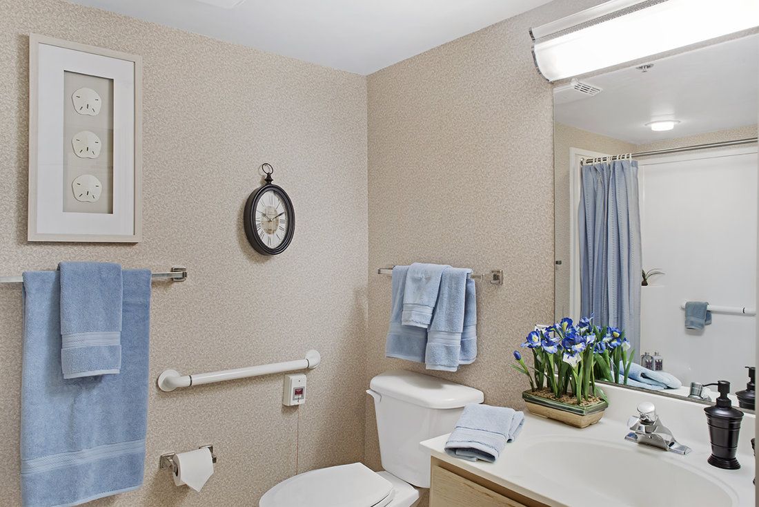 A well-kept bathroom featuring a neatly organized sink area with blue towels and decorative flowers.