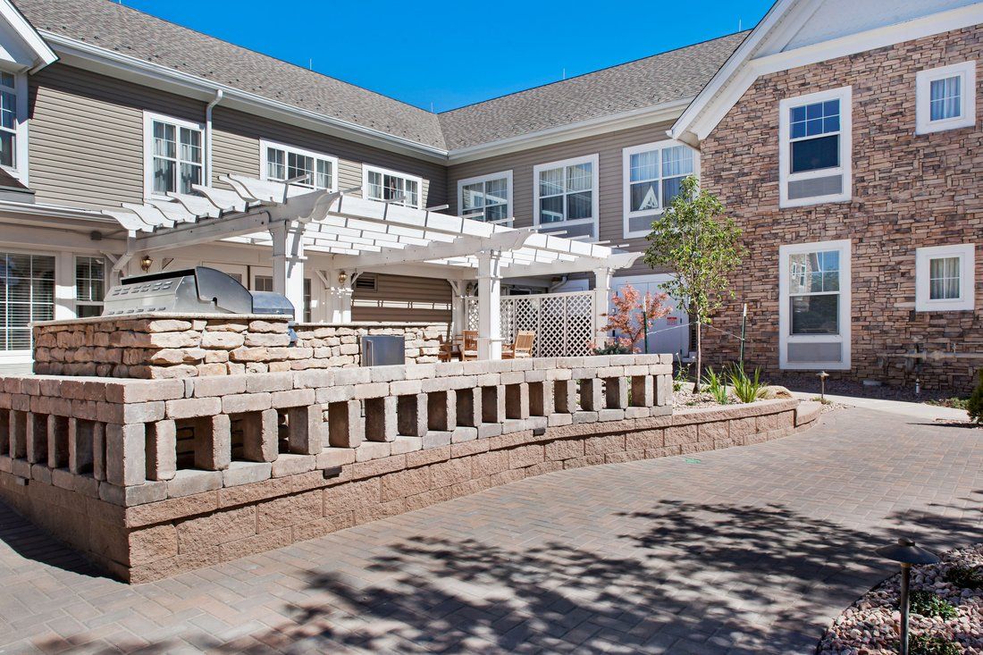 A modern residential building with a courtyard featuring a pergola and stone accents.
