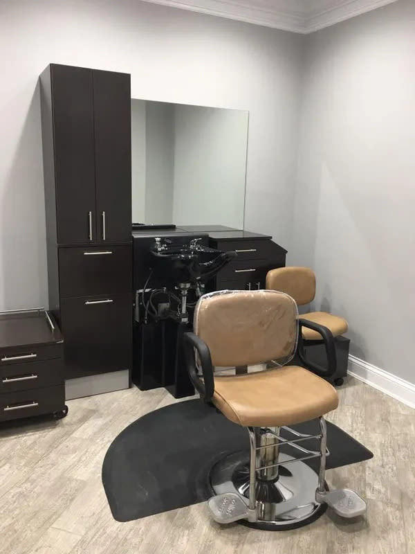 A well-organized hair salon station featuring a salon chair, mirror, and cabinet.