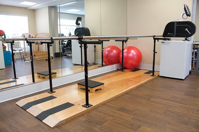 An exercise studio featuring a ballet barre, mirrors, and fitness equipment.