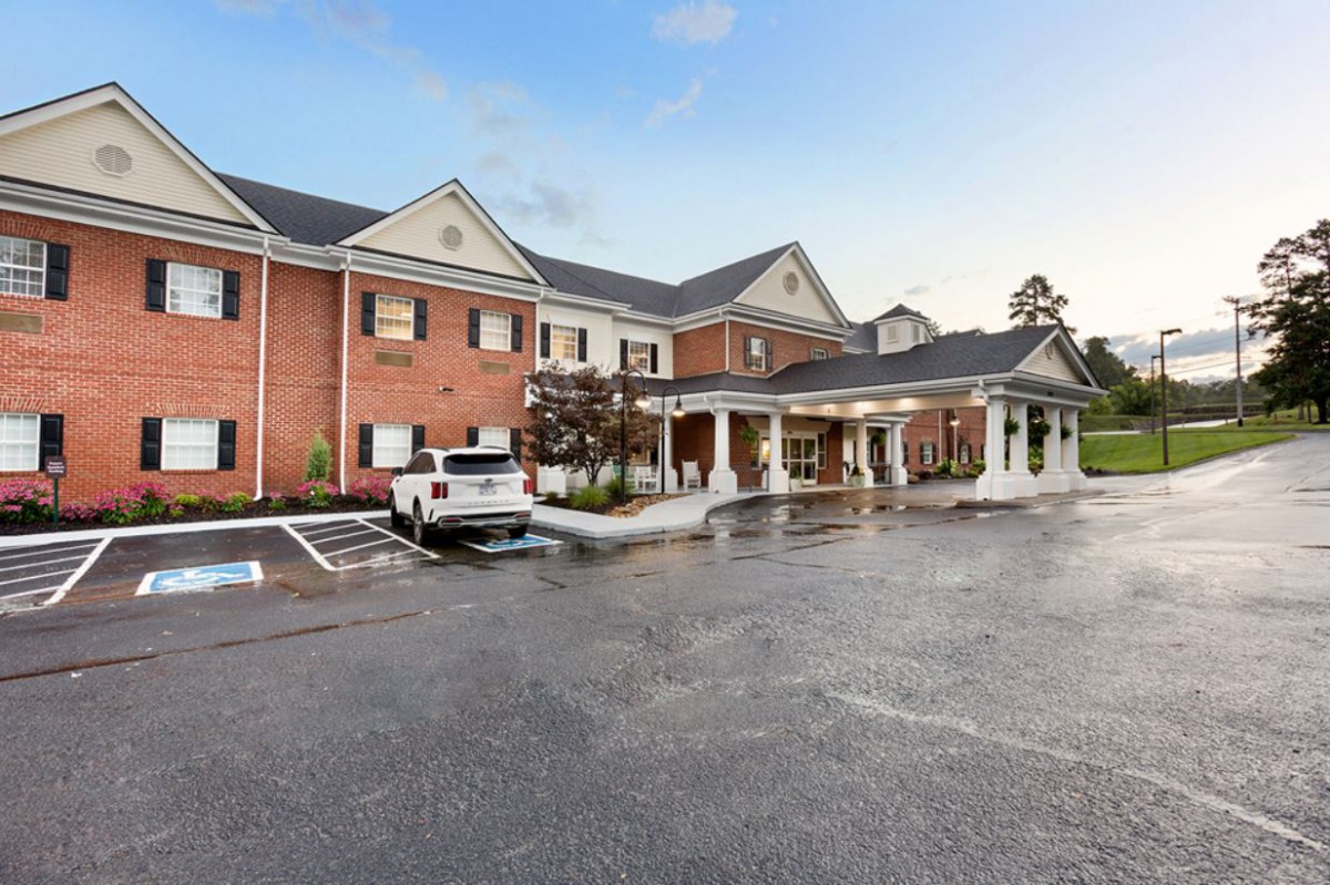 A two-story brick building with a covered entrance and adjacent parking lot.