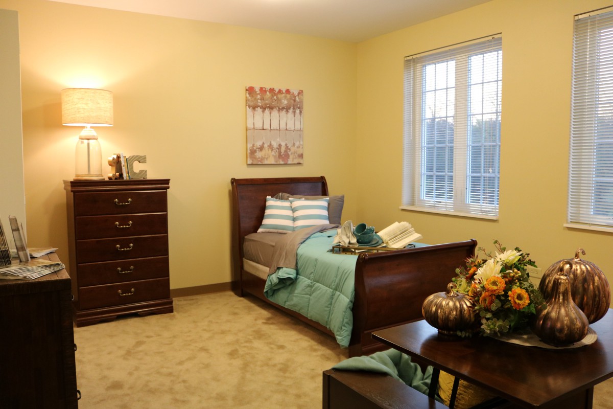 A cozy bedroom with a wooden bed, dresser, and warm lighting.