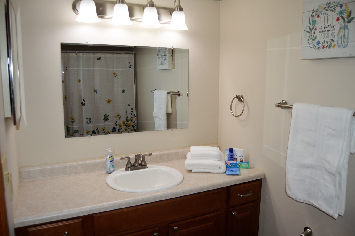 A tidy and well-lit bathroom with a mirror, sink, and neatly arranged towels.
