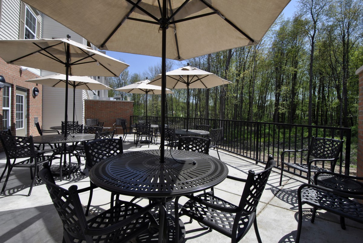 A sunny outdoor patio area with tables, chairs, and umbrellas.