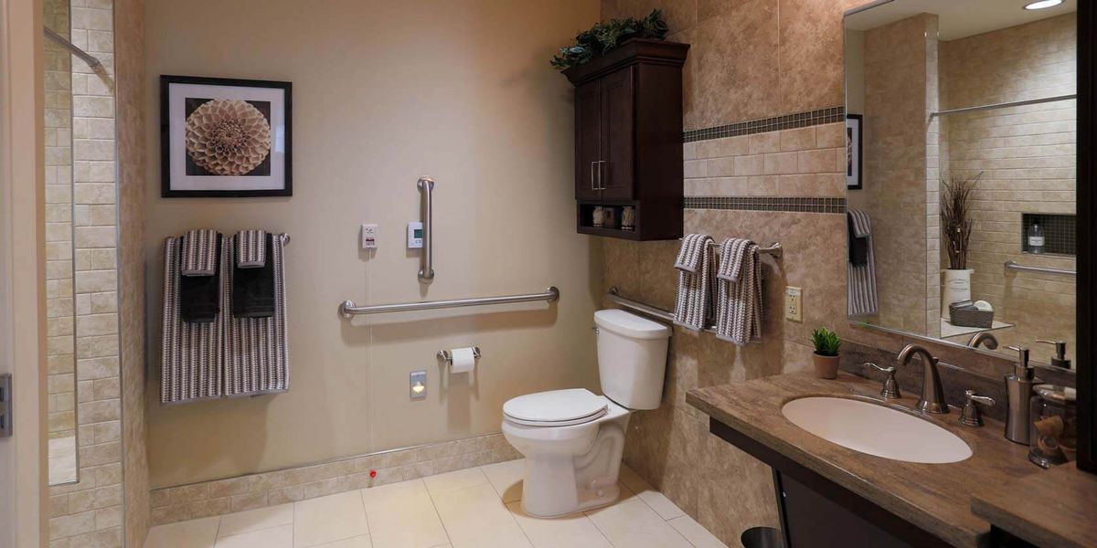An accessible bathroom with grab bars and neatly arranged towels.
