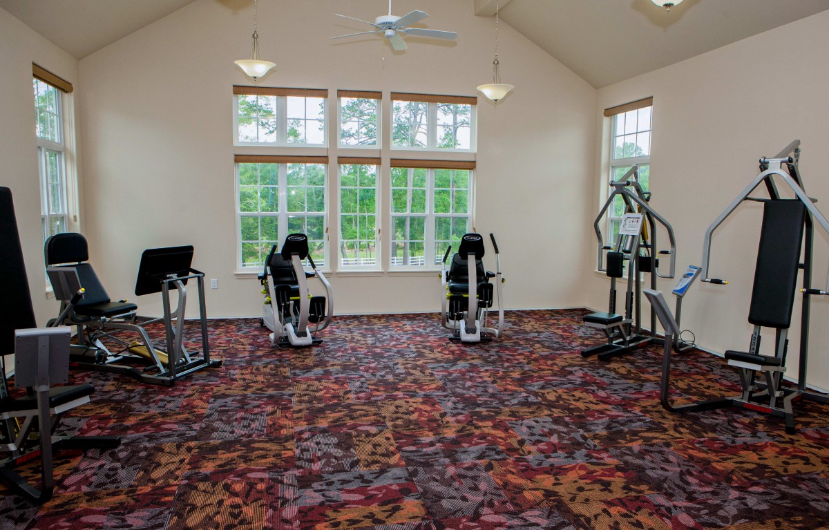 An indoor gym with various exercise machines on a carpeted floor.