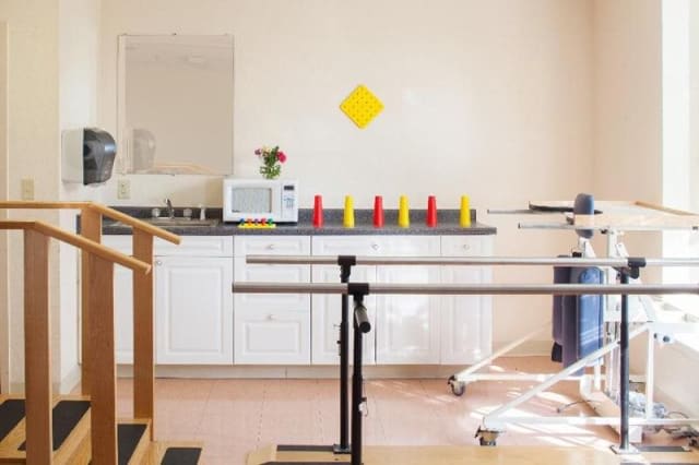 A rehabilitation room equipped with parallel bars and therapy tools.