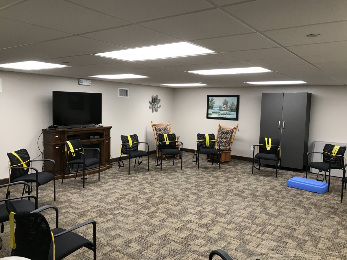 A waiting room with several chairs arranged in a circle, featuring a television and decorative elements.