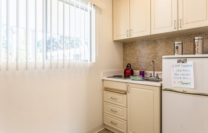 A compact apartment kitchen with light-colored cabinets and a small window.