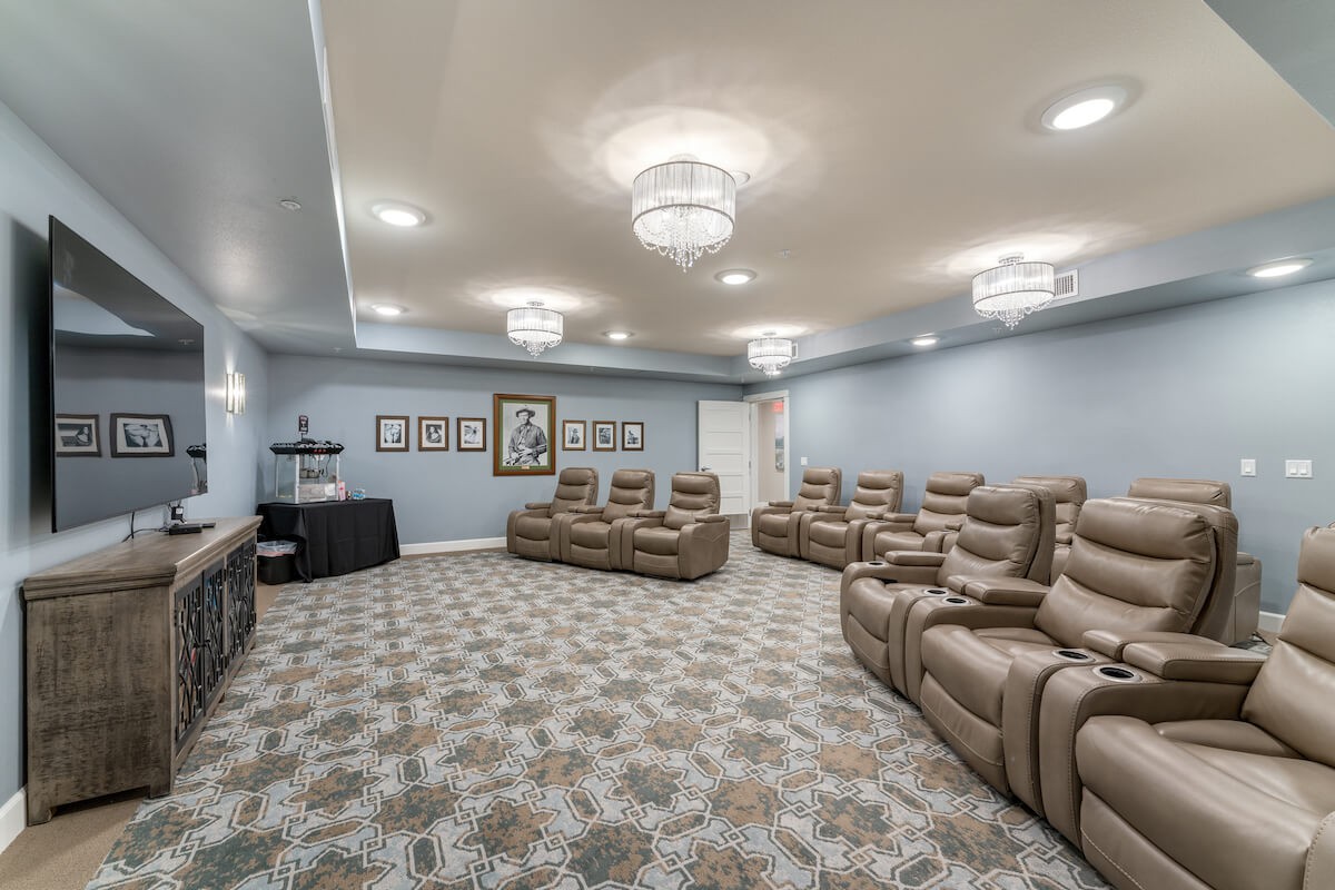 A cozy home theater room with comfortable recliner seating and elegant chandeliers.