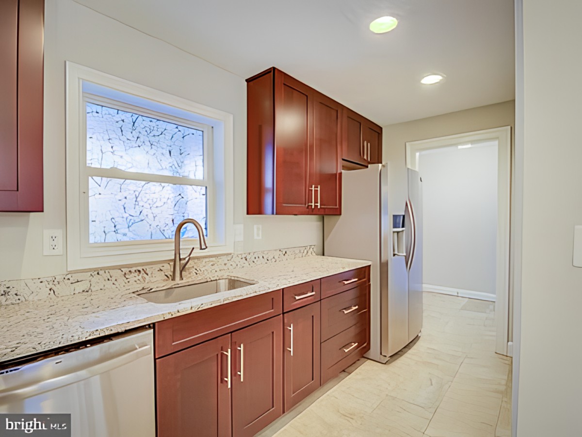 A modern kitchen with wooden cabinets, a marble countertop, and stainless steel appliances.