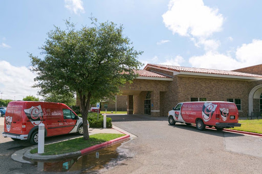 A view of a commercial building with parked vehicles and a tree in front.