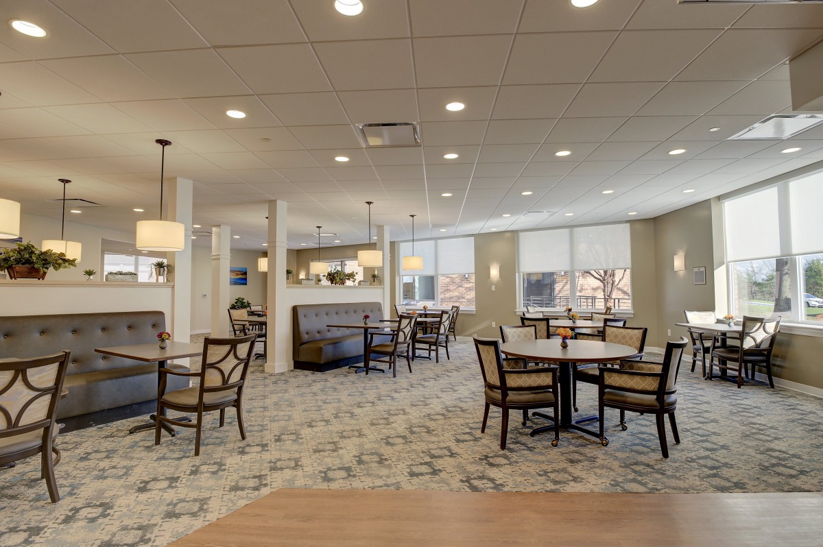 A modern dining area with tables and chairs, illuminated by overhead lighting.