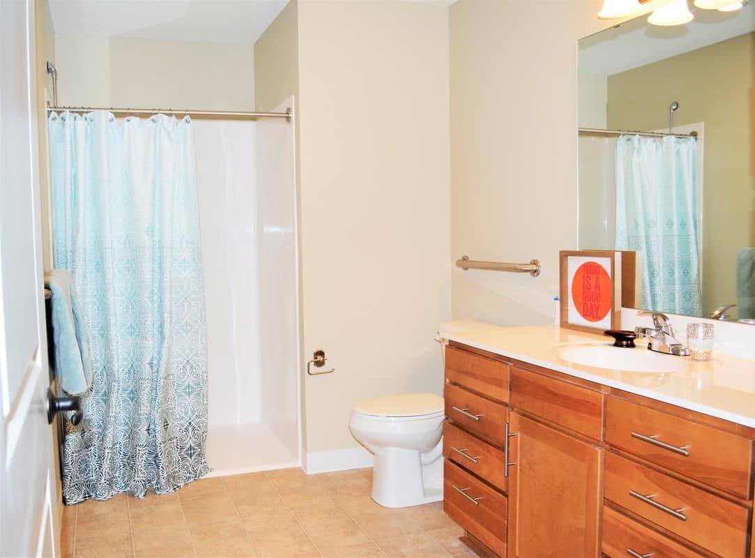 A clean and spacious bathroom with a shower, toilet, and wooden cabinets.