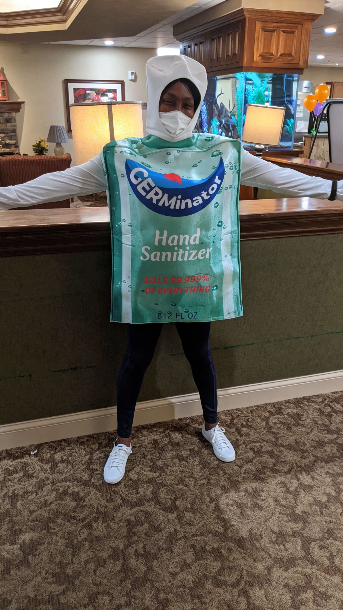 Person dressed in a hand sanitizer costume labeled 'GERMinator' with arms outstretched.
