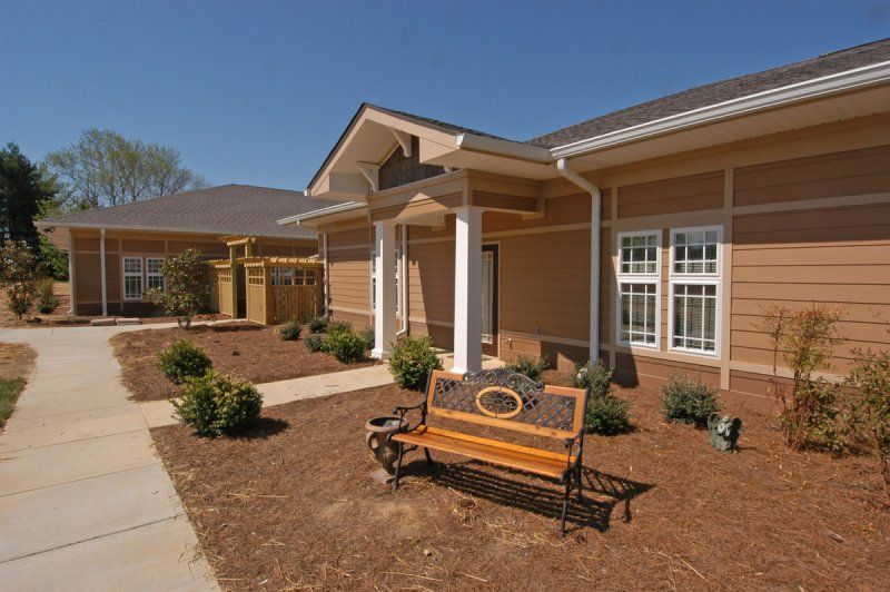 A modern building with a landscaped front yard and a wooden bench under a clear blue sky.