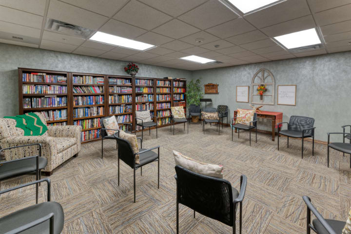 A library meeting room with chairs arranged in a circle and bookshelves lining the walls.