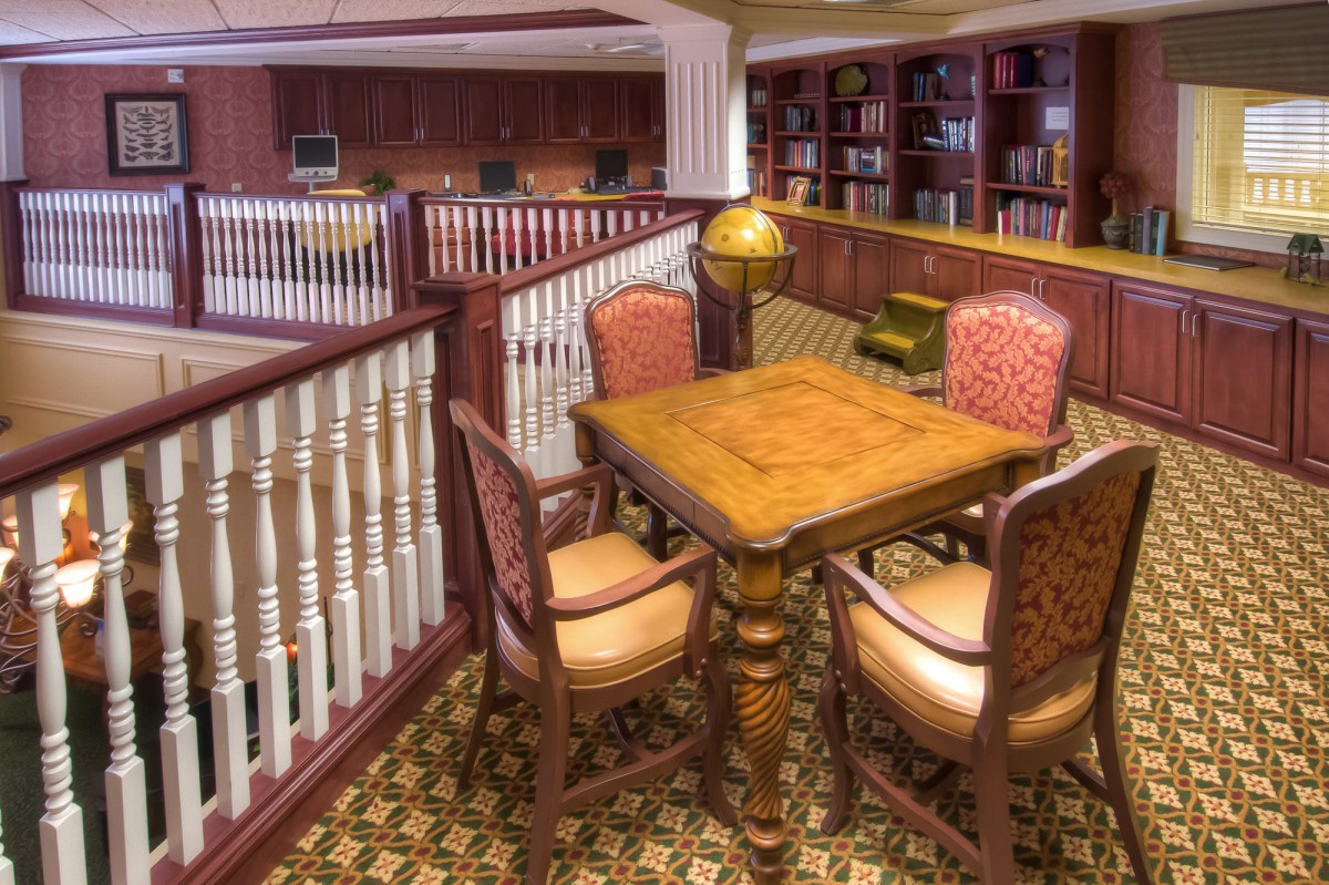 A cozy library corner with a wooden table and chairs, surrounded by bookshelves.