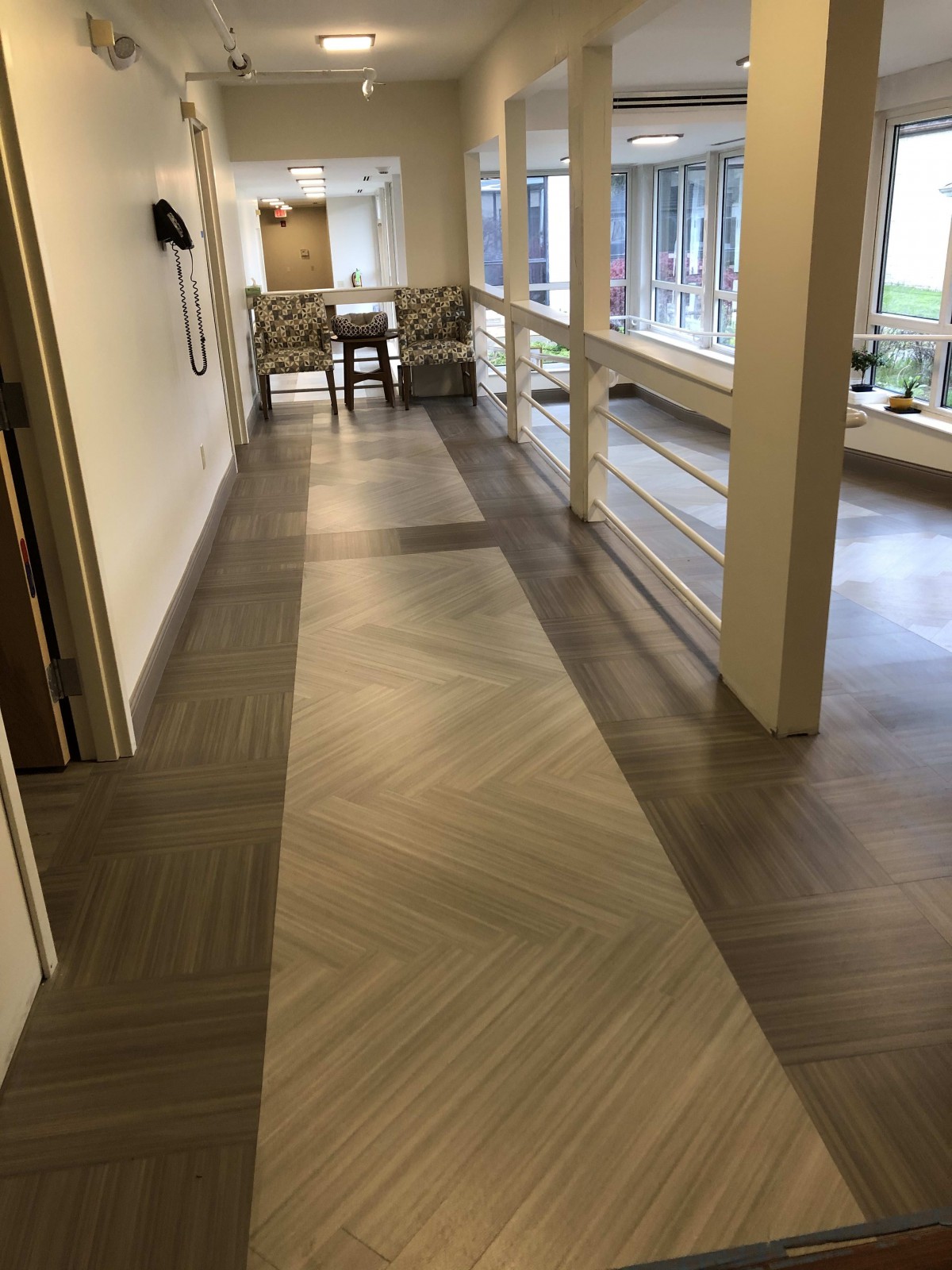 A well-lit hallway with modern flooring and large windows.
