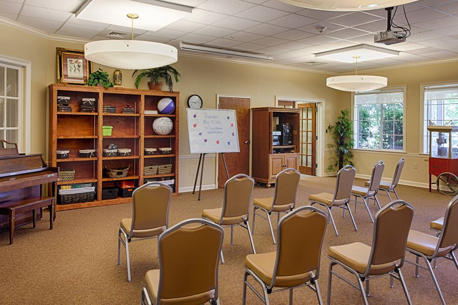 A conference room setup with chairs facing a whiteboard, shelves, and a television.