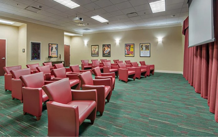 An empty auditorium with red chairs arranged in rows and posters on the walls.