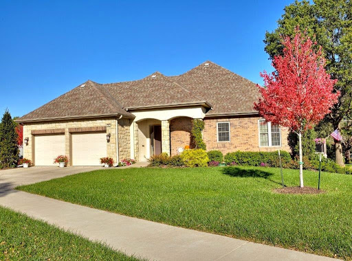 A beautiful brick home with a well-maintained lawn and vibrant fall colors.