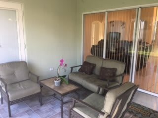 A cozy patio with comfortable seating and a small table adorned with an orchid.