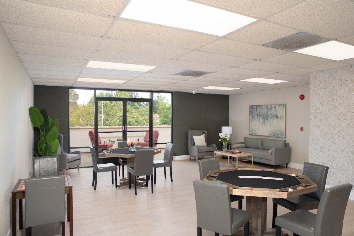 A modern lounge area with tables, chairs, and large windows offering a view of the outdoors.