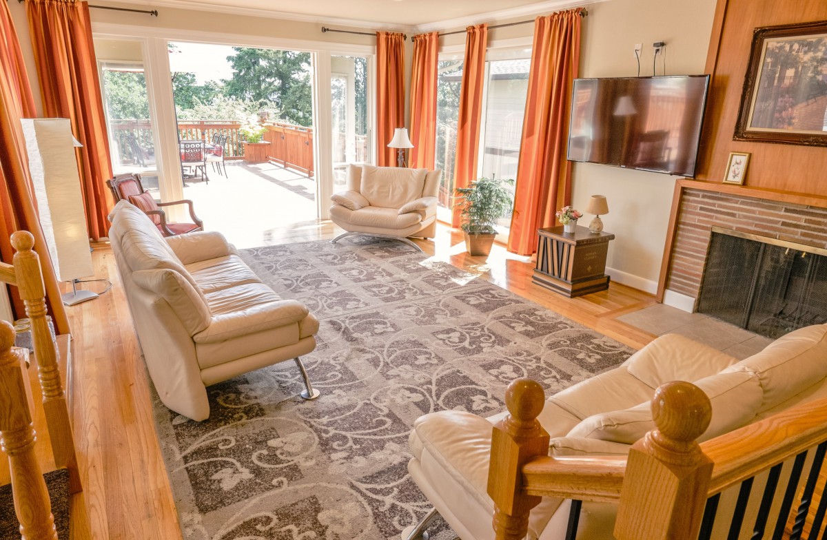 A spacious and bright living room with comfortable seating, a large rug, and floor-to-ceiling windows letting in plenty of natural light.