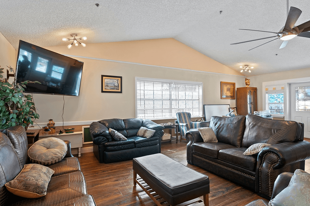 A cozy living room with leather sofas, a mounted television, and wooden floors.