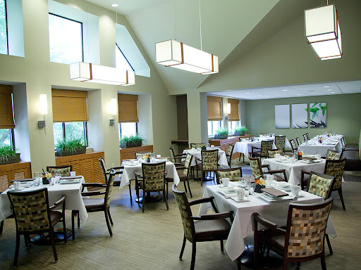 A spacious and elegantly designed dining area with well-set tables, modern lighting, and a warm ambiance.