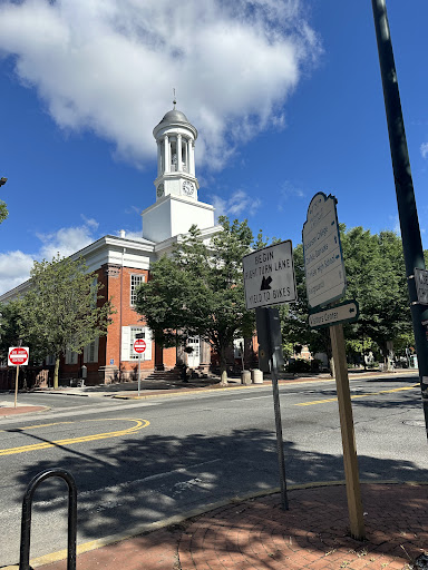 A view of a prominent building with a clock tower against a blue sky dotted with clouds.