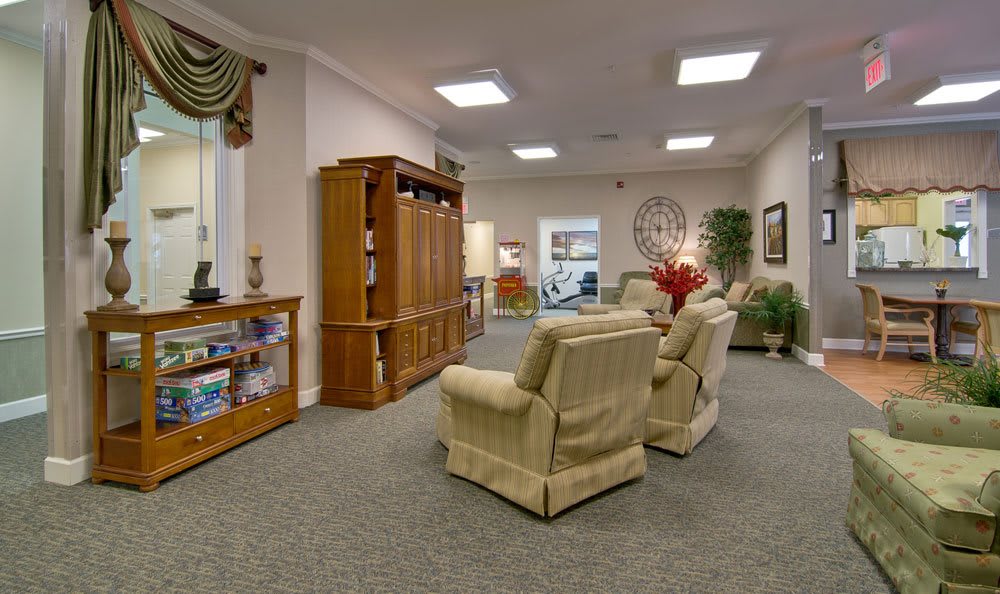 A cozy living room with comfortable chairs, a wooden bookshelf, and a cabinet.