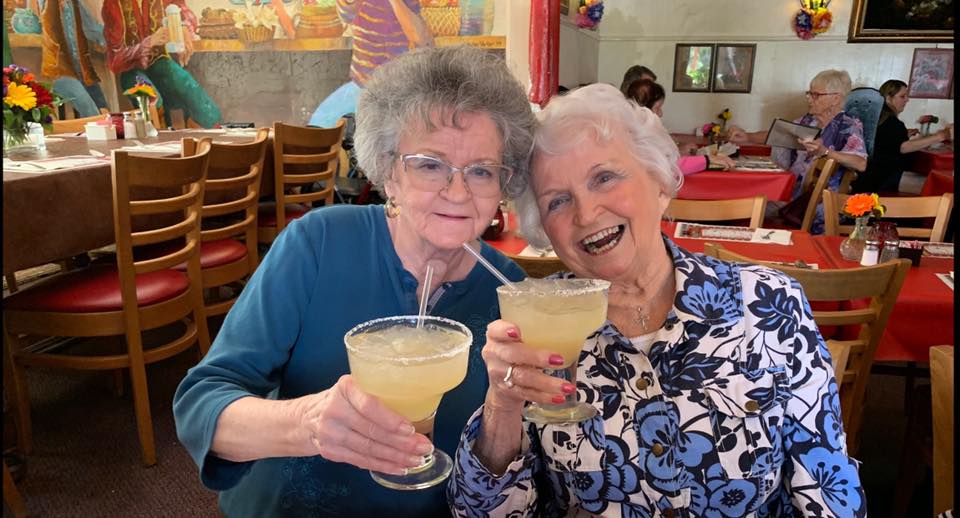 Two elderly women enjoying margaritas together at a restaurant.