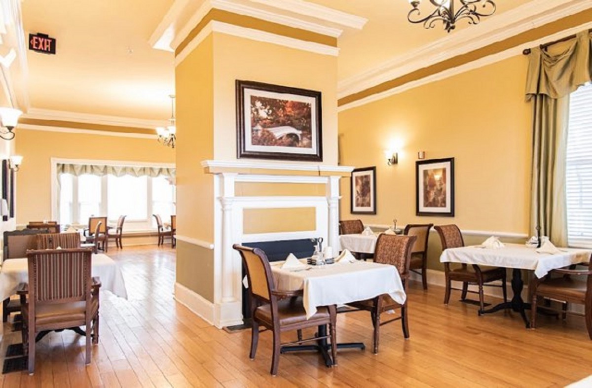 A warmly lit restaurant dining area with neatly arranged tables and elegant decor.
