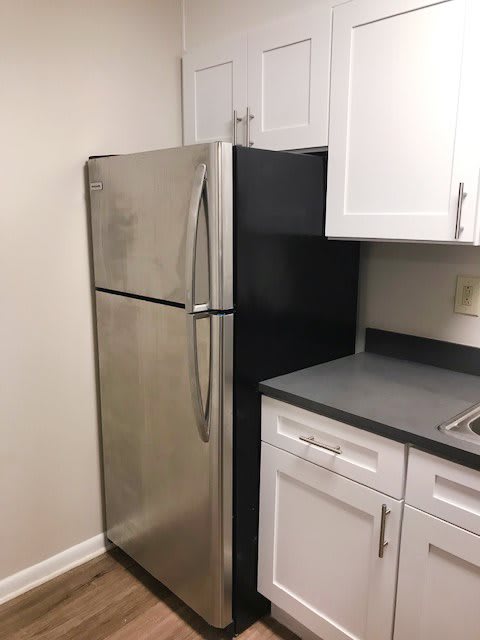 A stainless steel refrigerator in a modern kitchen with white cabinets.