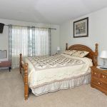 A cozy bedroom featuring a wooden bed frame, bedside tables with lamps, and decorative curtains.