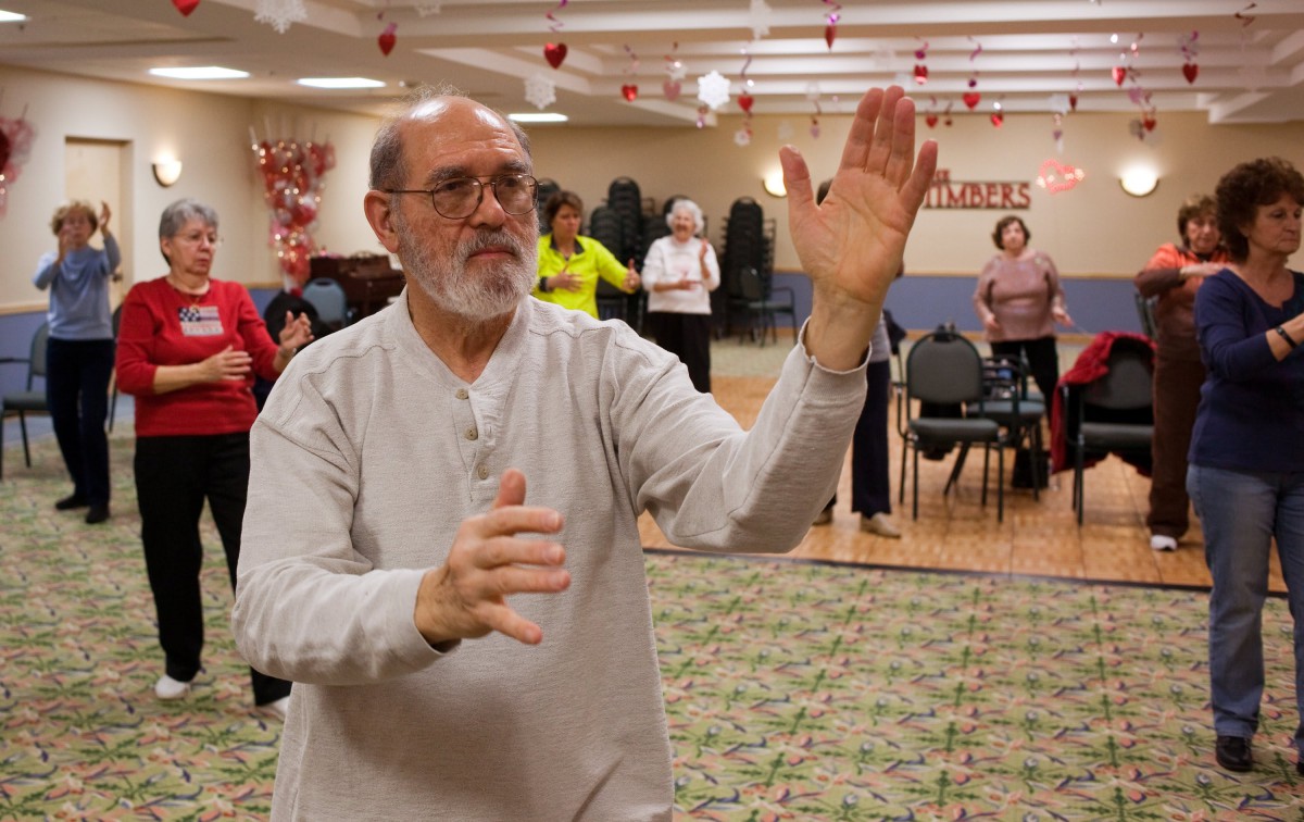A group of senior citizens practicing Tai Chi indoors for health and wellness.