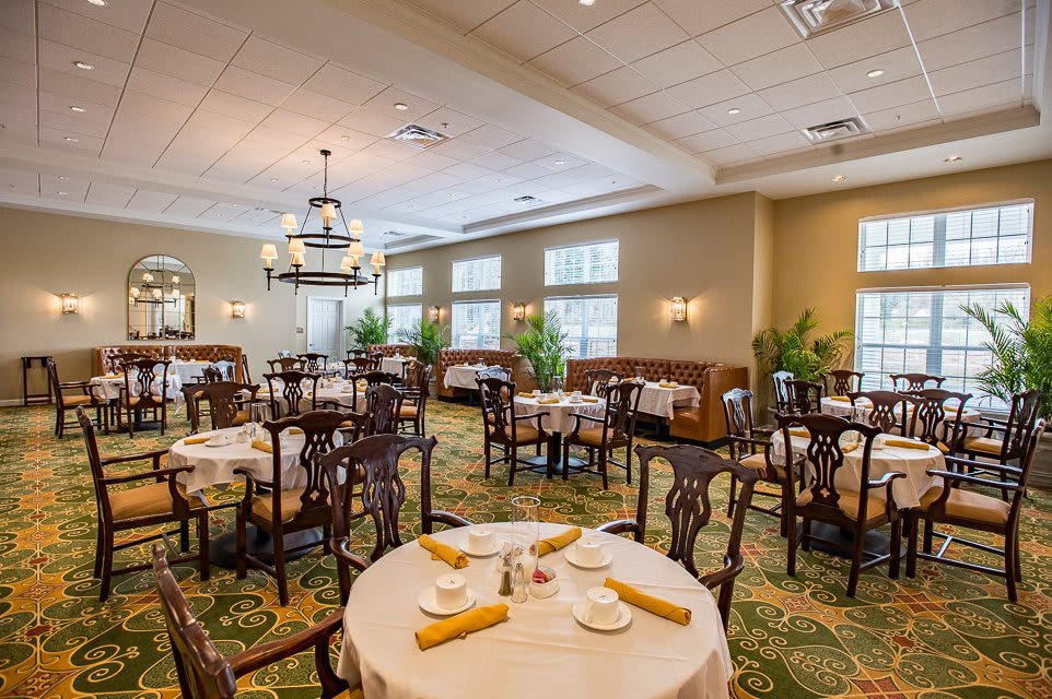 An elegant dining room with neatly arranged tables and chairs, featuring sophisticated lighting.