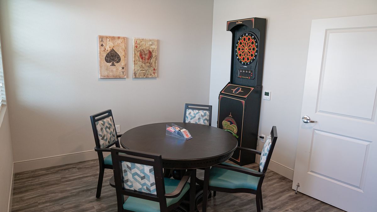A cozy game room featuring a round table with chairs, wall art, and a dartboard.